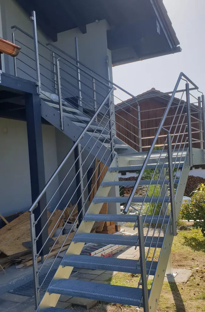 Verzinkte Metalltreppe  90 Grad abgewinkelt, mit Edelstahlgeländer, Zwischenpodest und Gitterroststufen.