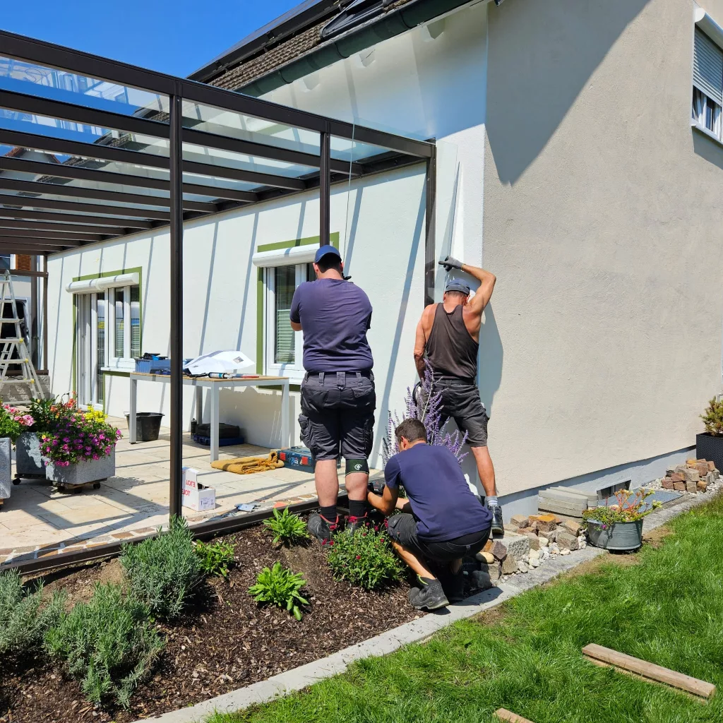 Montage einer Seitenverglasung an einem Terrassendach. Die Seitenteile dienen als Regenschutz und Windschutz.