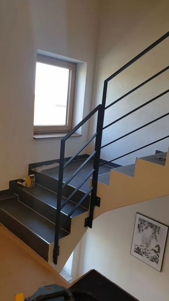 Montage des ersten Geländerteils an einer Betontreppe.