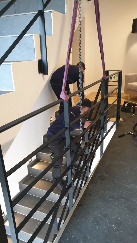 pulverbeschichtete Geländerfelder werden an eine Betontreppe montiert und verbunden. 