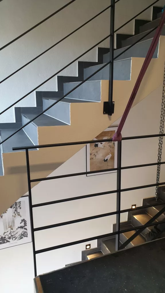 Flachstahlgeländer, anthrazit pulverbeschichtet im Farbton DB703 wird an einer Betontreppe befestigt.